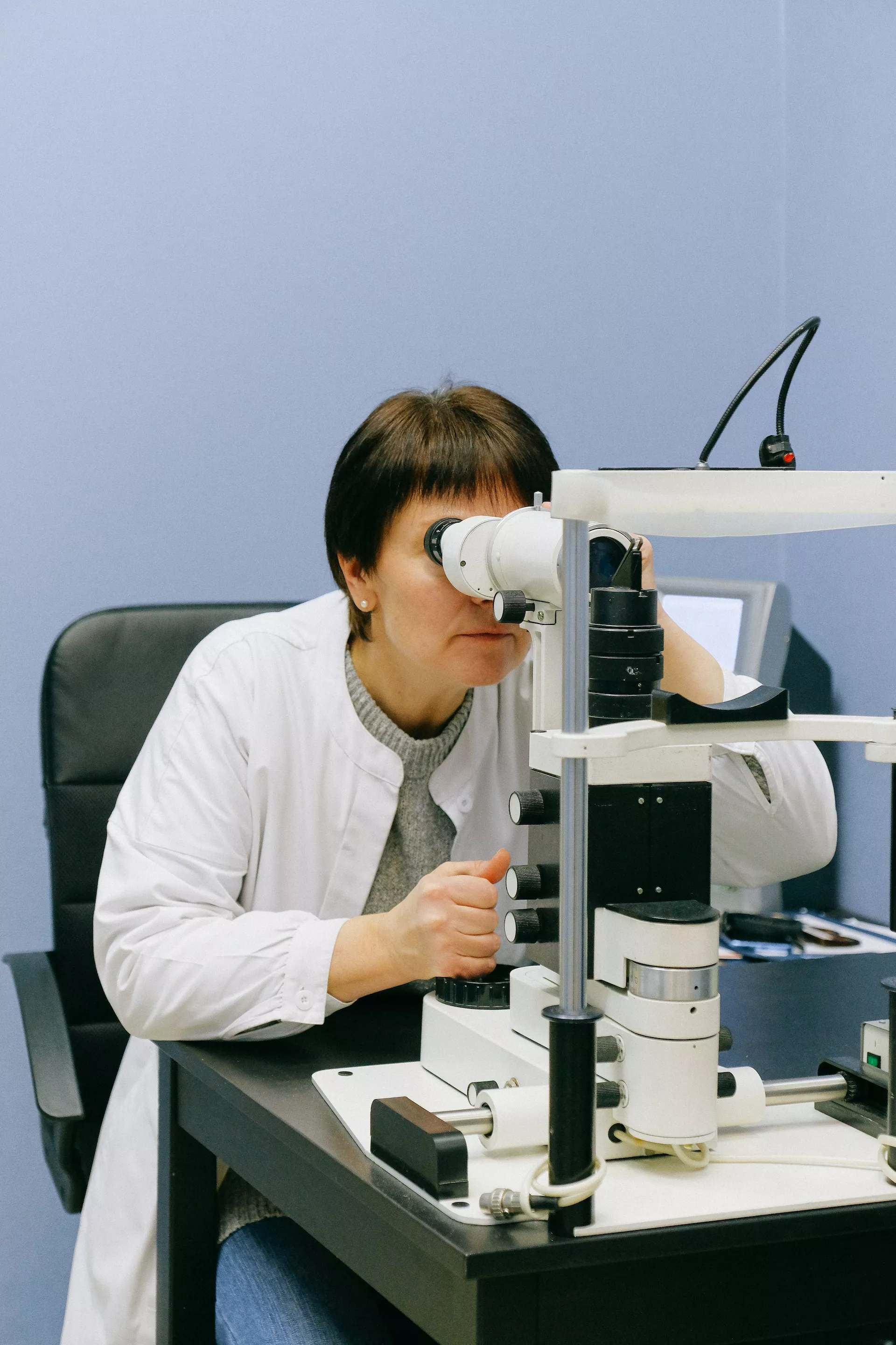 Investigadora Anónima Mirando A Través Del Microscopio De Lámpara De Hendidura. Foto de Anna Shvets